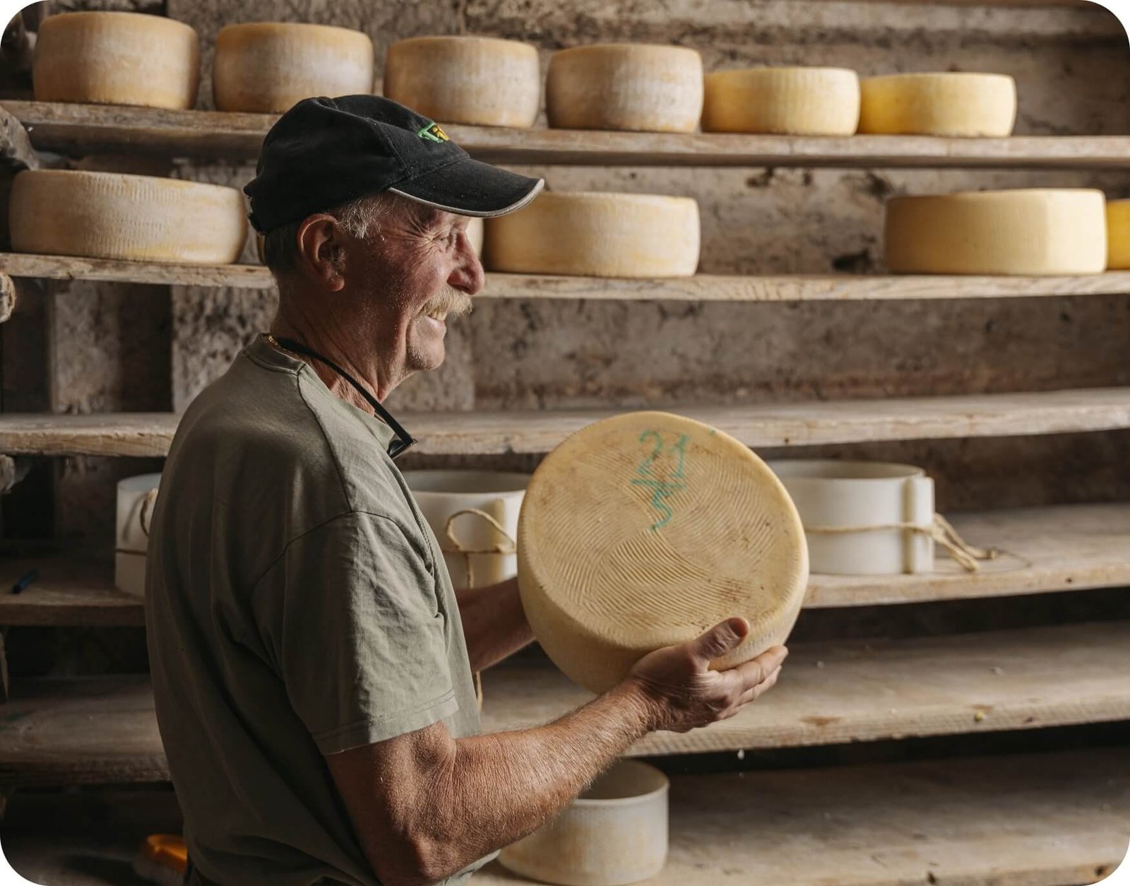 Casaro controlla forma di formaggio stagionato in cantina