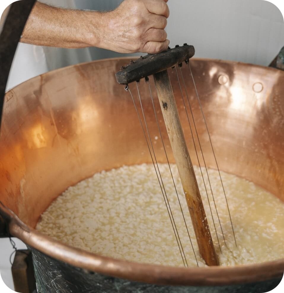 Casaro rompe la cagliata in caldaia di rame per fare il formaggio
