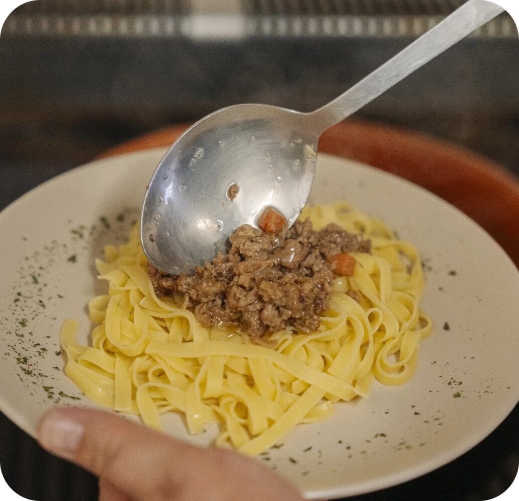 Tagliatelle al ragù servite con mestolo