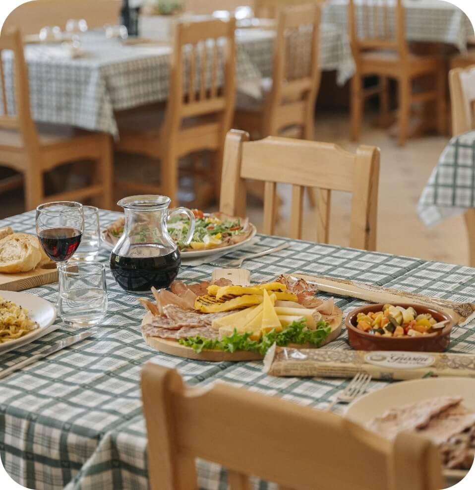 Tagliere con salumi, formaggi e vino rosso per degustazione all’aperto in montagna.